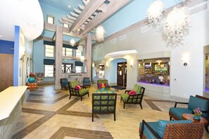 Eine geräumige Lobby mit hoher Decke, einer Bar und verschiedenen Sitzgelegenheiten.
