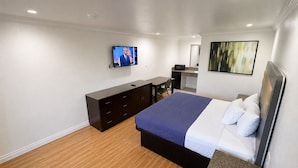 Une chambre d’hôtel équipée d’un lit, d’un bureau, d’une télévision et d’une kitchenette.