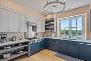 A modern kitchen with a built-in stove, white cabinets, and a large window offering a view of the outdoors. - Santa Fe Santuario- Perfect Views, Kiva Fireplace (Santa Fe)