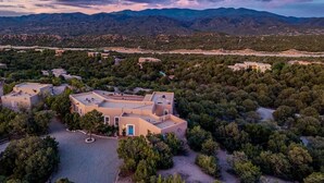 A large, modern building with multiple sections, surrounded by dense greenery and mountains in the background. - Santa Fe Santuario- Perfect Views, Kiva Fireplace (Santa Fe)
