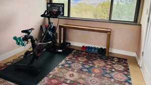 Ett hemmagym med en motionscykel, hantlar och en mönstrad matta.