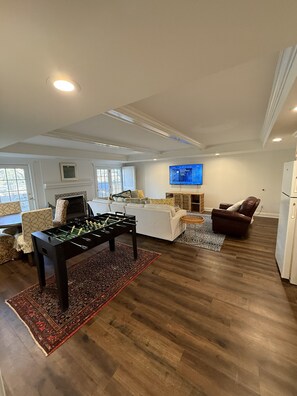 Ein modernes Wohnzimmer mit einem Kicker, einem Kamin, einem Fernseher und einem braunen Ledersofa.