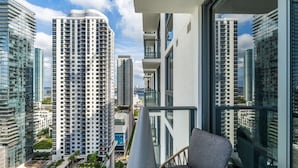 Een hoog gebouw met een balkon, een stoel en een zwembad.