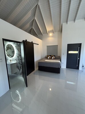 A modern bedroom with a bed, a bathroom with a marble vanity, and a door. - Lux Apartment Stay (Willemstad)