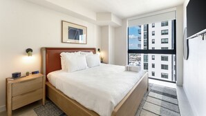 A hotel room with a bed, bedside table, nightstand, and a large window offering a city view. - Crosby Miami WTC 1BR/1BA Downtown Gem #2713 (Miami)
