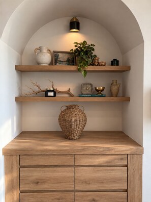 Ein Holzschrank mit einer großen gewebten Vase, einer Uhr und einer Pflanze auf einer Ablagefläche.