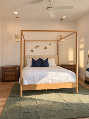 Ein Himmelbett mit Holzrahmen, weißer Bettwäsche und zwei Nachttischen mit Lampen.