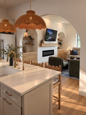 Una cocina moderna con una isla central, armarios de madera y un televisor integrado sobre la chimenea.