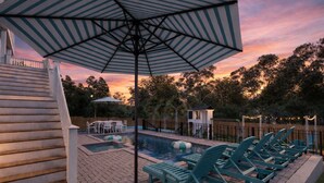 Ein Garten mit Schwimmbad, Liegestühlen und einer überdachten Terrasse.