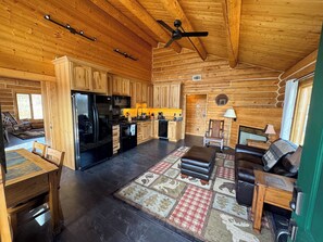 A log cabin interior with a kitchen, dining area, and living room.