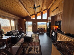 A log cabin interior with a living room, dining area, and kitchen.