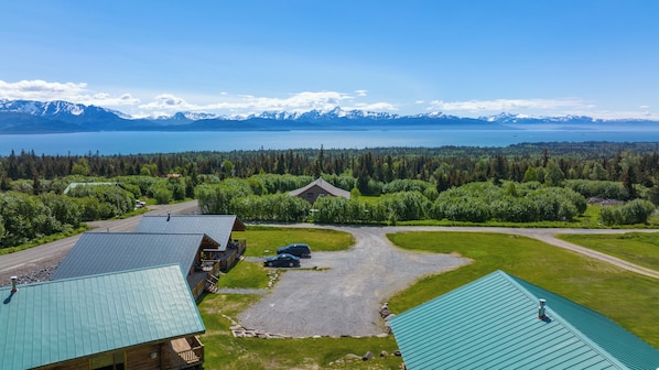 A lodge with multiple cabins, a gravel driveway, and a view of a lake and mountains.
