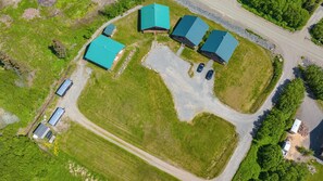 An aerial view of a property with multiple buildings, a large open grassy area, and a winding road.