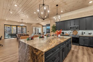 Une cuisine moderne avec des meubles sombres, des plans de travail en granit et un grand îlot central.