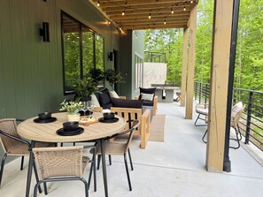 A covered patio with a round table, wicker chairs, and a seating area with cushions. - 5BR Luxury Cabin w/ Indoor Pool, Theater & Hot Tub (Sevierville)