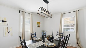 Ein Esszimmer mit einem schwarzen Tisch, weißen Wänden und einer Deckenleuchte.