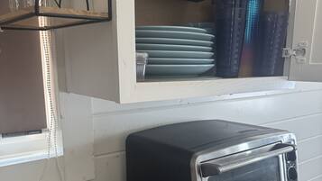 A kitchen with a Farberware toaster oven, a wooden cutting board, and a white bowl.