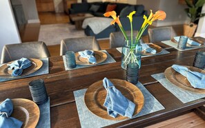 A dining table set with plates, napkins, and a vase with flowers.