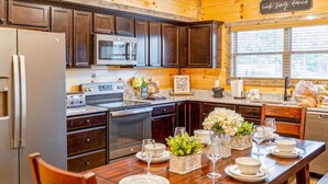 Una cocina de madera con armarios oscuros, electrodomésticos de acero inoxidable y una mesa de comedor para seis comensales.