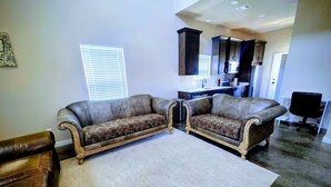 A living room with a sectional sofa, a coffee table, and a kitchen in the background.