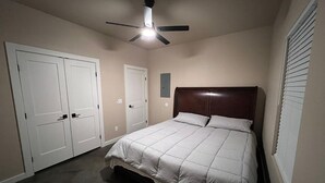 A bedroom with a bed, a ceiling fan, and a closet.