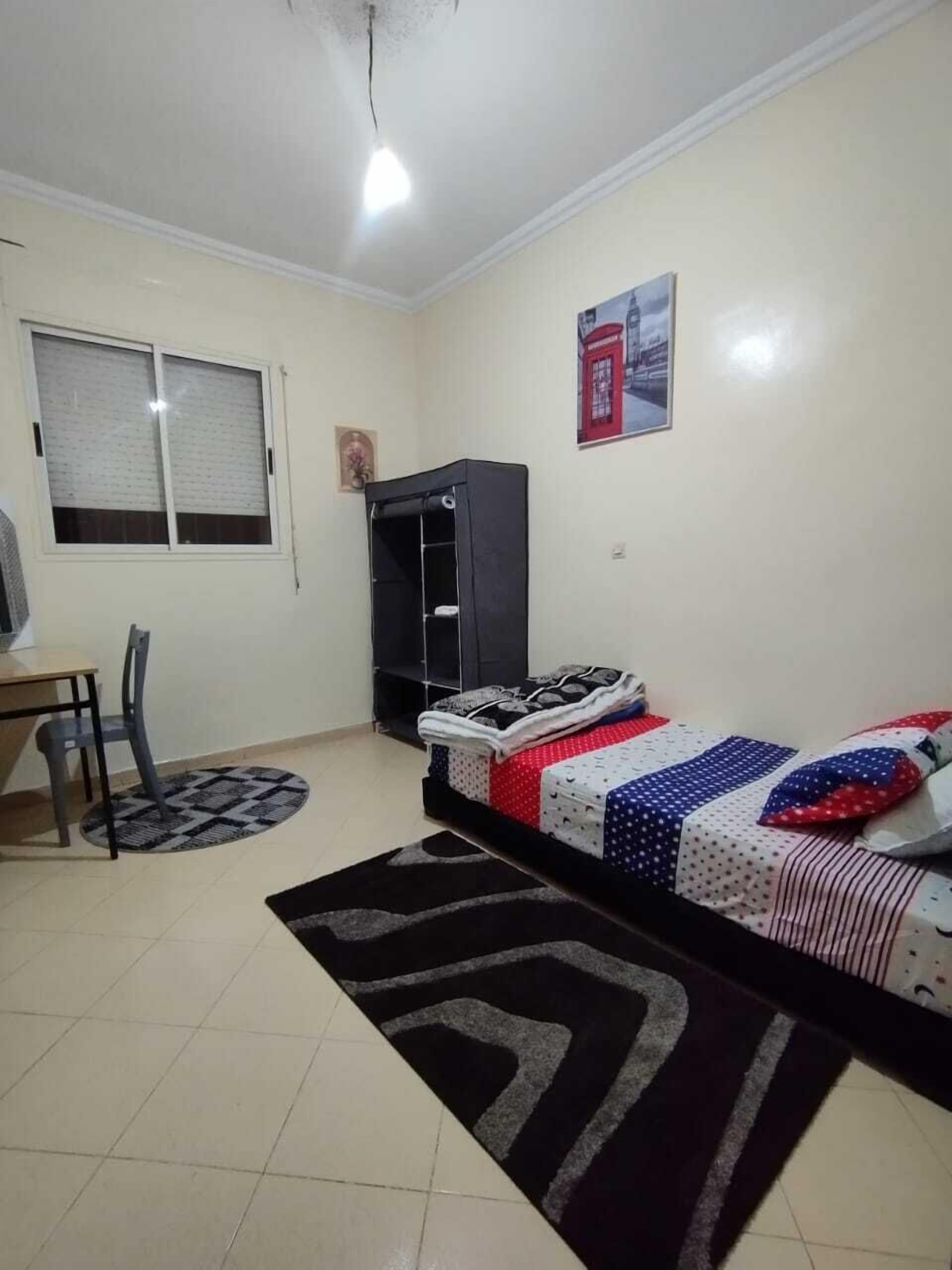 A small, clean room with a bed, a desk, a chair, and a wardrobe.