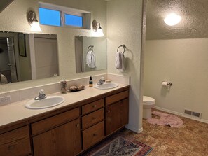 Un baño con tocador de doble lavabo, espejo, toallero y retrete.