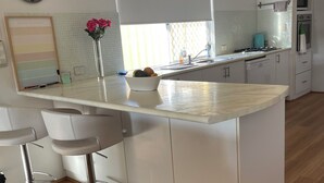 A modern kitchen with a central island, white cabinetry, and a stainless steel sink. - Why have a room when for the same price you can have a whole gorgeous house! (Lakelands)