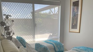 A bedroom with a large bed, a small round table with decorative balls, a window with a view of the outside, and a framed picture on the wall. - Why have a room when for the same price you can have a whole gorgeous house! (Lakelands)