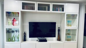 A modern entertainment unit with a flat-screen TV, multiple shelves for books and decorative items, and integrated storage drawers. - Why have a room when for the same price you can have a whole gorgeous house! (Lakelands)