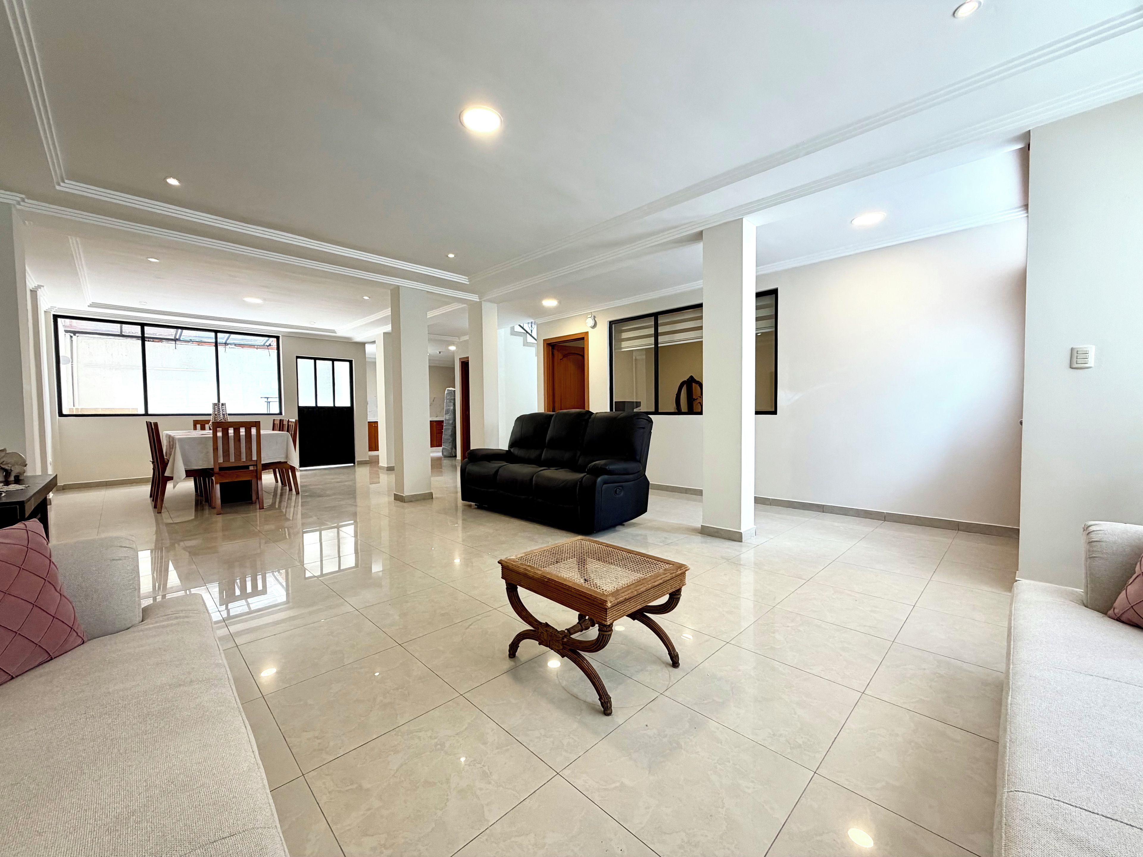A spacious living area with a sofa, a dining table with chairs, and a coffee table.