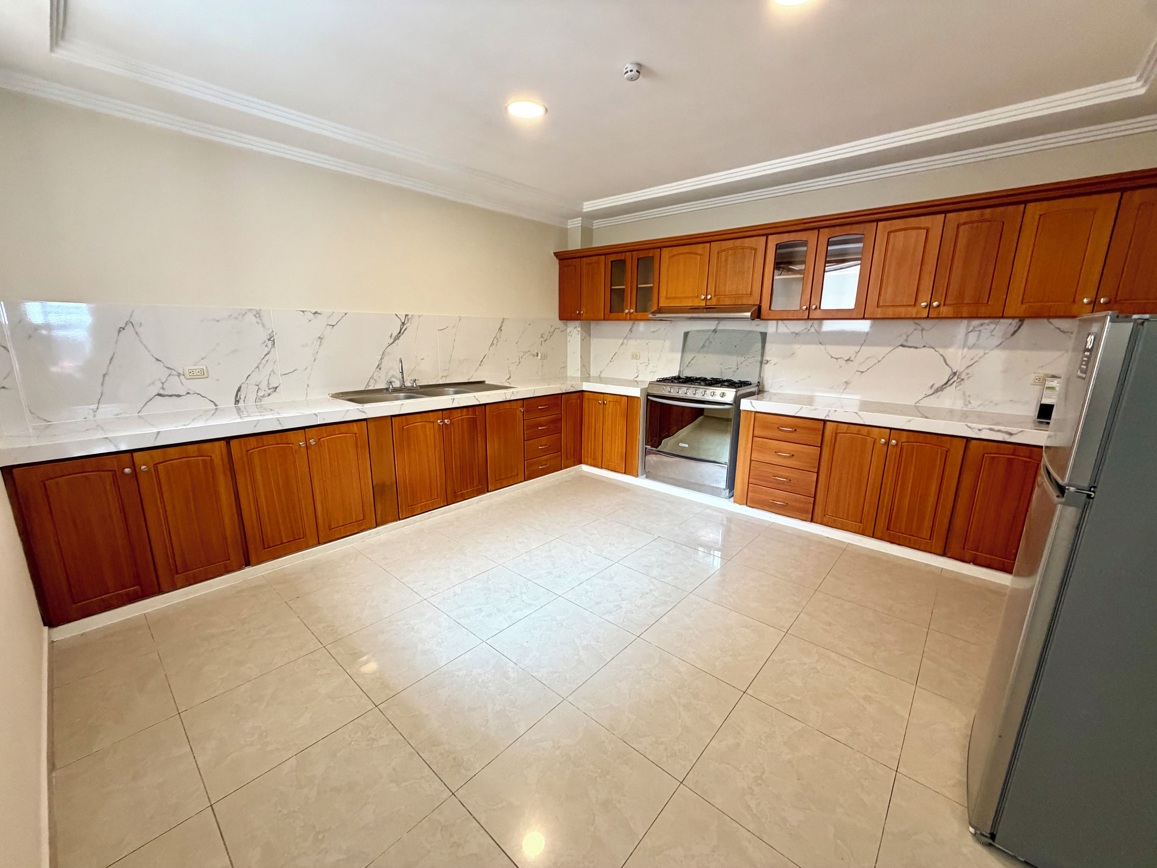 A kitchen with wooden cabinets, a stainless steel stove, and a marble backsplash.