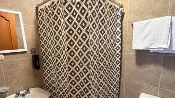 A bathroom with a shower curtain, a sink, a toilet, and a towel rack.