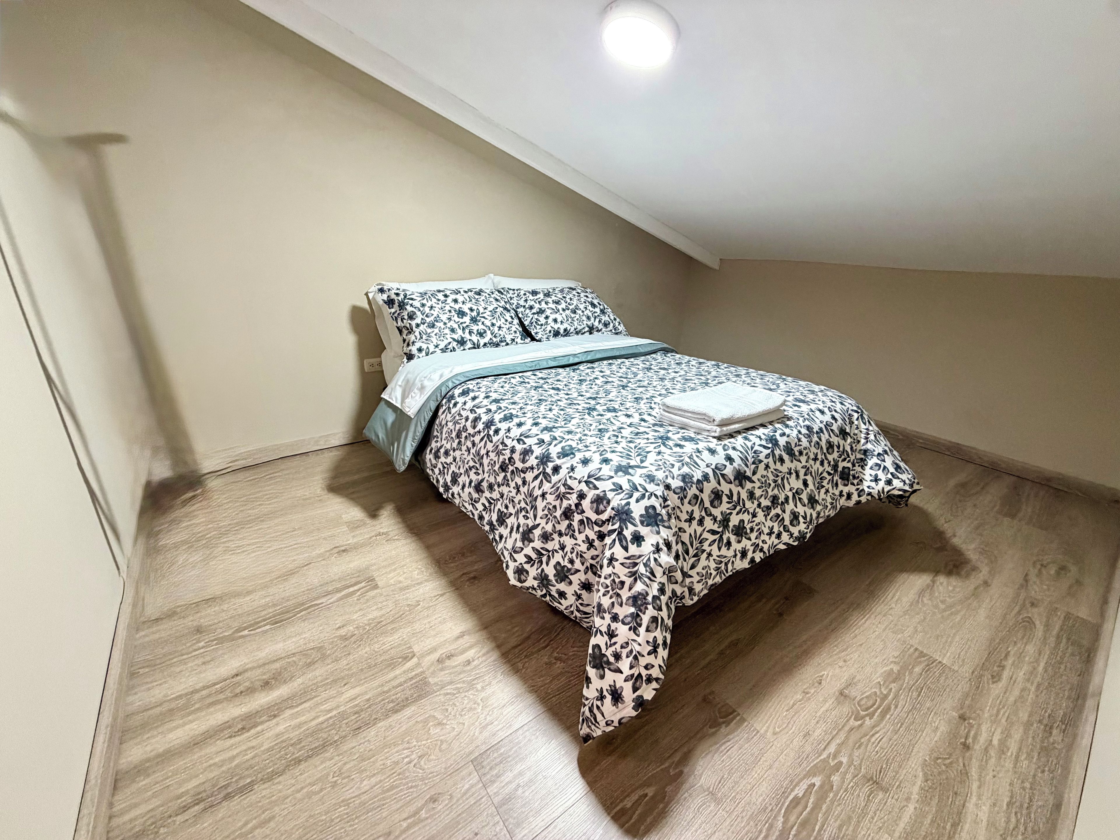 Un dormitorio con cama, mesita de noche y luz de techo.