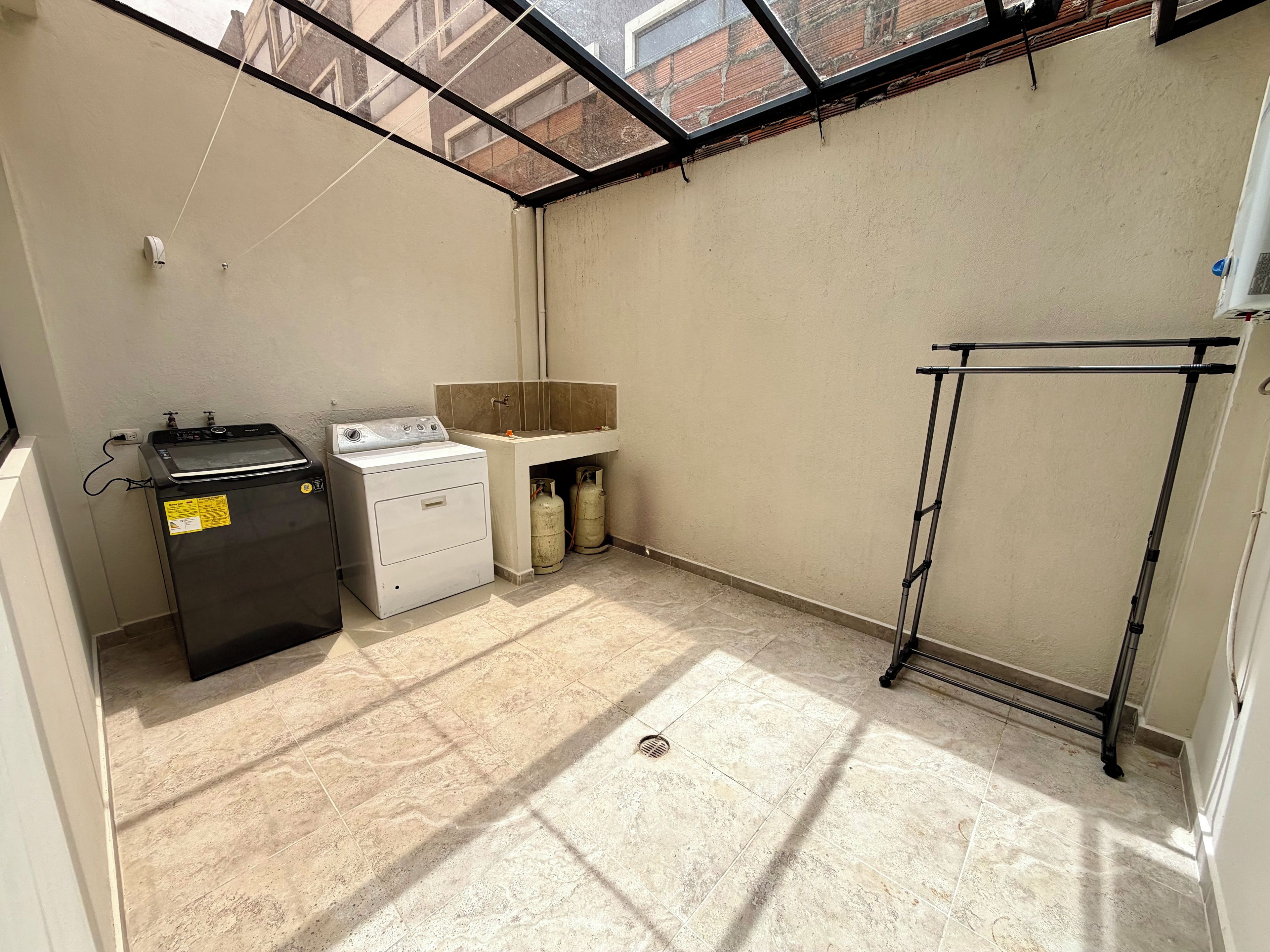 A laundry area with a washing machine, a sink, and gas cylinders.