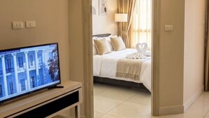 Ein Hotelzimmer mit Fernseher, Bett, Schreibtisch und Bad.