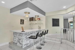 A modern kitchen with a marble island, bar stools, and a hanging light fixture. - Beautiful Luxury Waterfront Heated Pool Home in Fort Lauderdale (Fort Lauderdale)