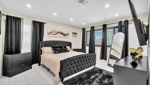 Une chambre moderne avec un grand lit, une coiffeuse avec un miroir et une commode.
