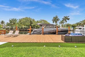 A yacht docked at a marina with a wooden deck, lounge chairs, and a grassy area. - Beautiful Luxury Waterfront Heated Pool Home in Fort Lauderdale (Fort Lauderdale)