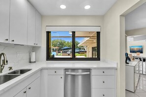 A modern kitchen with white cabinetry, a stainless steel sink, and a dishwasher. - Beautiful Luxury Waterfront Heated Pool Home in Fort Lauderdale (Fort Lauderdale)