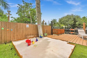 A backyard with a wooden deck, a sandy play area, and a wooden fence. - Beautiful Luxury Waterfront Heated Pool Home in Fort Lauderdale (Fort Lauderdale)