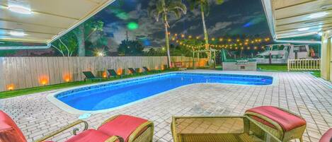 An outdoor swimming pool with lounge chairs and a covered area.