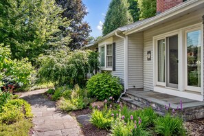 A residential property with a stone pathway leading to a house with a covered porch.