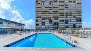 Ein Schwimmbad mit Blick auf einen Hochhaus im Hintergrund.
