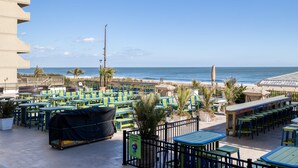 An outdoor seating area with tables and chairs, overlooking the beach and ocean. - Plaza 109 (Ocean City)