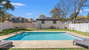 A backyard with a swimming pool, a barbecue grill, and a picnic table.