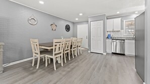 A modern kitchen with white cabinets, a stainless steel dishwasher, and a granite countertop.
