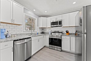 A modern kitchen with white cabinets, stainless steel appliances, and a window providing natural light. - 3BR Sleeps 8 | Walk to Beach | Pool | 508/2 (North Myrtle Beach)