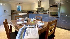 A modern kitchen with a dining table set for four, equipped with a refrigerator, oven, and microwave. - LES CLAIRIANS - LE CANNET DES MAURES (LE CANNET DES MAURES)