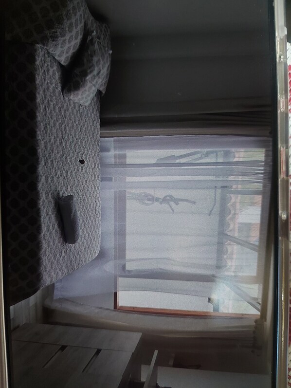 Een kamer met een bed, een raam en een kleine tafel.